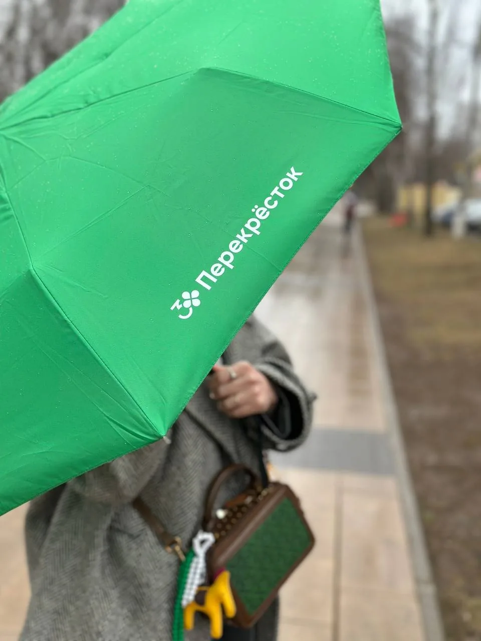 Зелёный зонт с логотипом «Перекрёсток» на улице